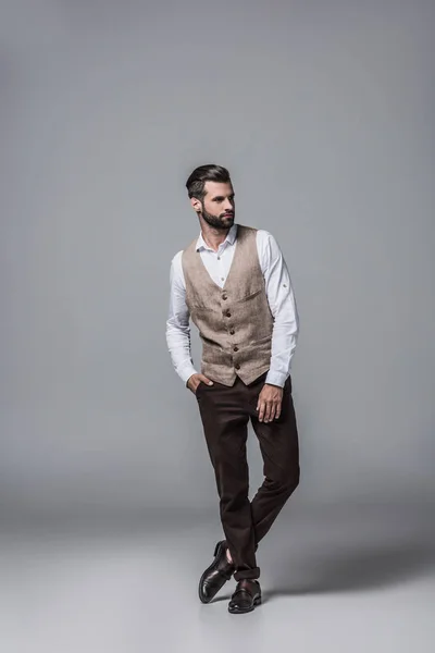 Bell'uomo barbuto in posa in elegante gilet elegante su grigio — Foto stock