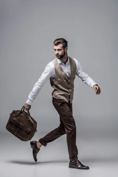 Hurry stylish man running with leather bag on grey — Stock Photo