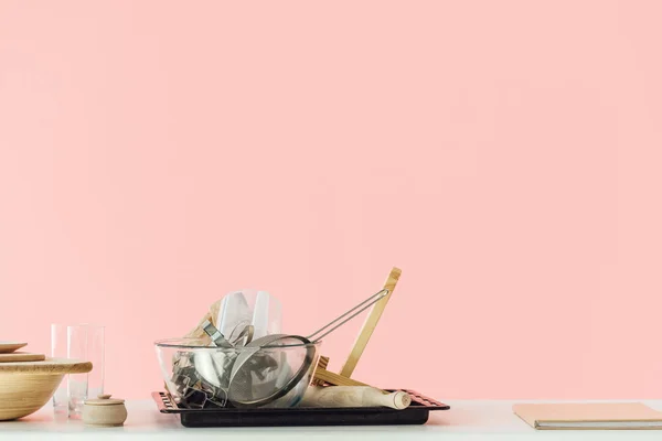 Varios utensilios de cocina desordenados en la mesa aislados en rosa - foto de stock