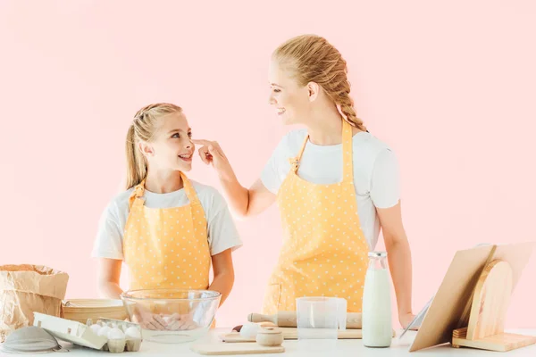 Mutter und Tochter spielen mit Mehl und bereiten Teig isoliert auf rosa — Stockfoto