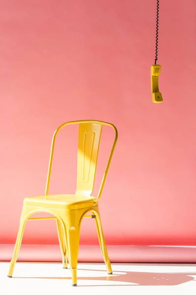 Chaise jaune et tube de téléphone sur rose — Photo de stock