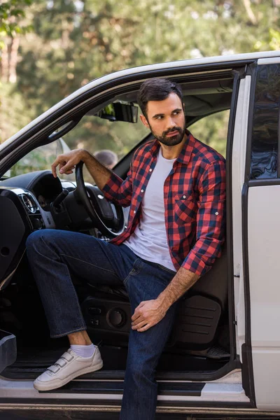 Bello autista barbuto seduto in pick-up camion nella foresta — Foto stock