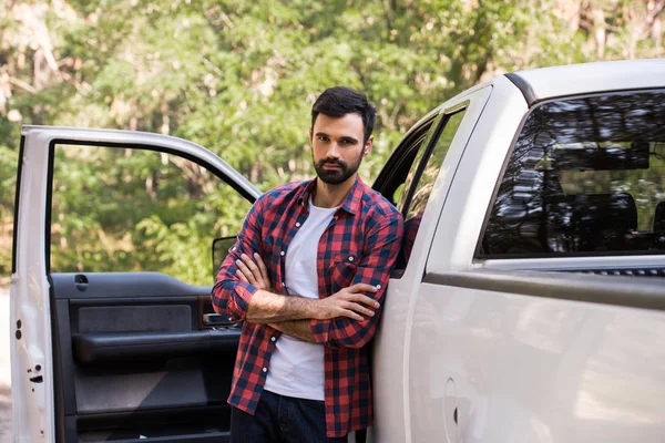 Confident driver with crossed arms standing at pickup truck in forest — Stock Photo