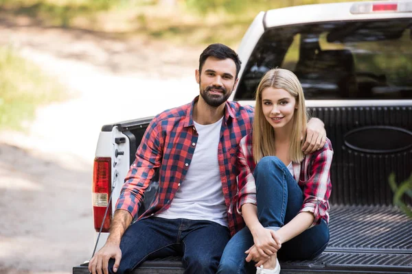 Smiling couple hugging and sitting together on pickup truck — Stock Photo