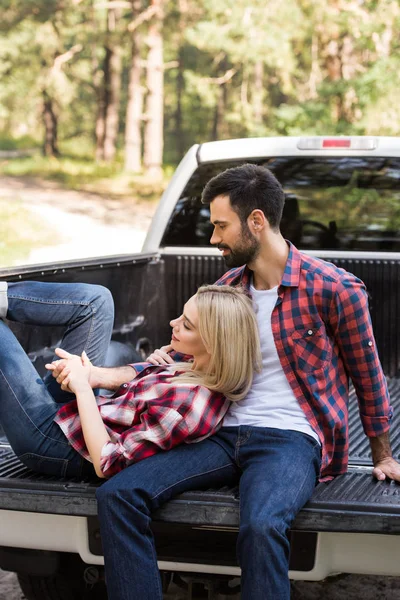 Glückliches Paar ruht sich auf Pickup-Truck im Wald aus — Stockfoto