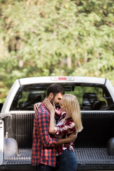 Belo jovem casal abraçando e indo para beijar perto de carro na floresta — Fotografia de Stock
