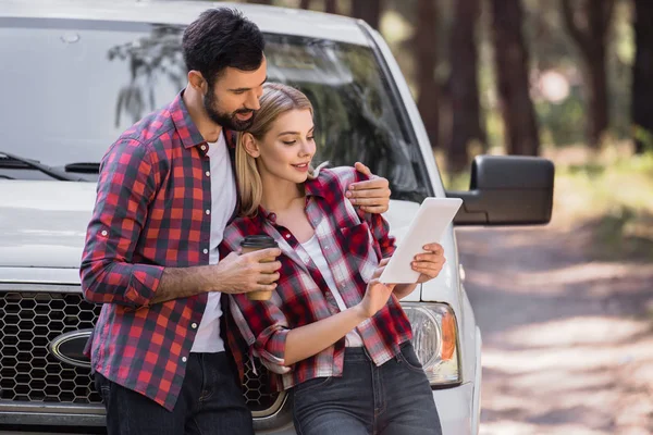 Abraço casal e usando tablet digital perto de pickup caminhão na floresta — Fotografia de Stock