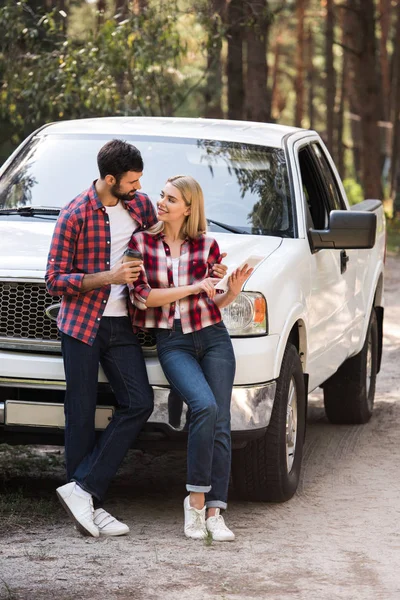 Couple using digital tablet and looking at each other near pickup truck in forest — Stock Photo