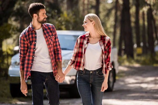 Couple heureux tenant la main et marchant dans la forêt — Photo de stock