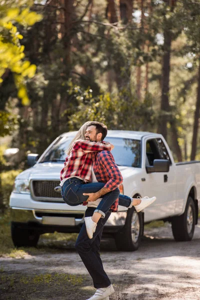 Casal animado se divertindo juntos na floresta com pickup caminhão atrás — Fotografia de Stock