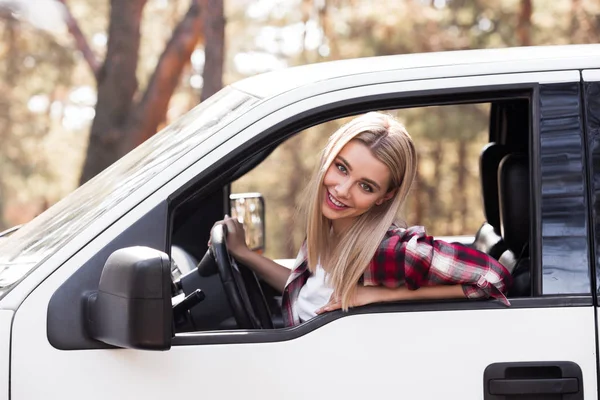 Beautiful young driver sitting in pickup truck in forest — Stock Photo