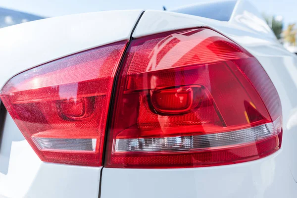 Close up of red rear headlight of white new car on street — Stock Photo