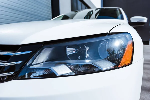 Close up of headlight of white new car on street — Stock Photo