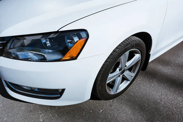 Cropped image of headlight and wheel of white new car on street — Stock Photo