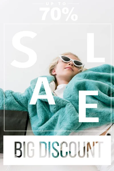Beautiful stylish child in turquoise fur coat lying with black shopping bag on white, big discount sale banner concept — Stock Photo