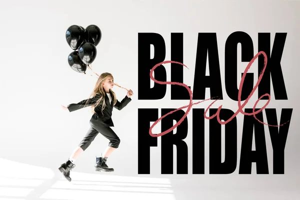 Fashionable child in trendy suit jumping with black balloons on grey, black friday banner concept — Stock Photo