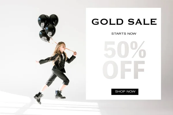 Fashionable child in trendy suit jumping with black balloons on grey, gold sale banner concept — Stock Photo