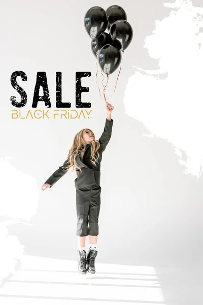 Dreamy child jumping or flying with black balloons on grey, black friday sale banner concept — Stock Photo