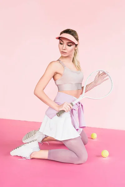 Pretty sportswoman in visor hat posing with tennis racket and balls on pink — Stock Photo