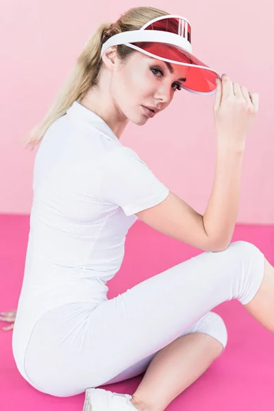Atleta femenina con estilo en sombrero de visera posando en rosa - foto de stock