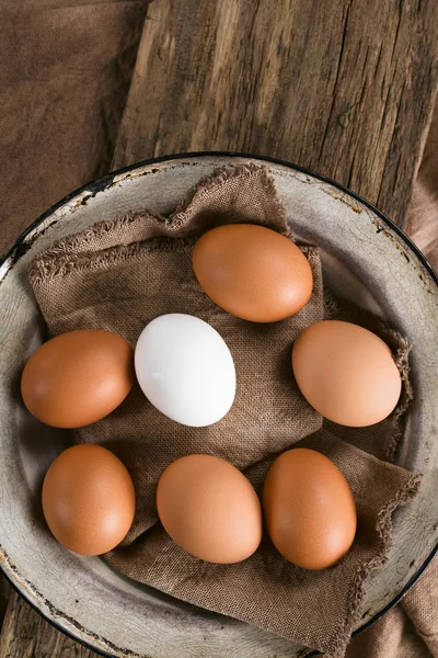 盘子里有一个白鸡蛋的生棕色鸡蛋 在头顶上拍照 选择性焦点 聚焦在鸡蛋顶部 — 图库照片