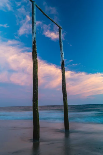 해질 녘에 해변에 있는 나무 기둥들 — 스톡 사진