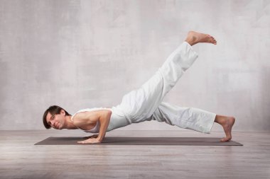 Beyaz elbiseli genç yoga egzersizi yapıyor.