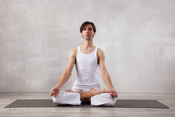 Ung Man Vita Kläder Gör Yoga Vardagsrummet Lotusposerar Meditation — Stockfoto