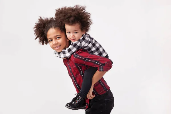 Teenage dívka dávat ji malé sestra a piggyback jízda — Stock fotografie