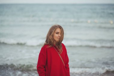 Kumsalda yürüyen kırmızı ceketli güzel bir kadın.