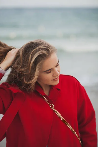 Hermosa mujer de abrigo rojo caminando por la playa — Foto de Stock