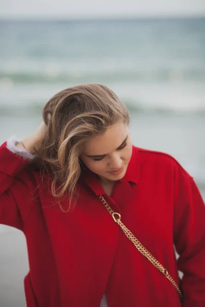 Hermosa mujer de abrigo rojo caminando por la playa — Foto de Stock