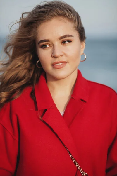 Hermosa mujer de abrigo rojo caminando por la playa —  Fotos de Stock