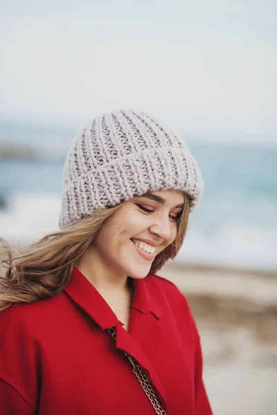 Hermosa mujer de abrigo rojo caminando por la playa — Foto de Stock