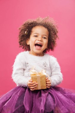 Happy little girl holding a shiny gift box clipart