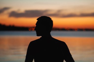 İnsan nehir kenarında gün batımını izlemekten zevk alır.