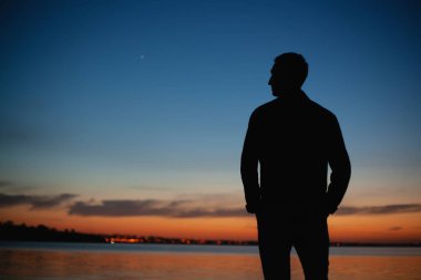 İnsan nehir kenarında gün batımını izlemekten zevk alır.