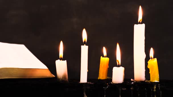 圣经和蜡烛上的旧木烧毁表 美丽的黑暗背景 宗教概念 — 图库视频影像