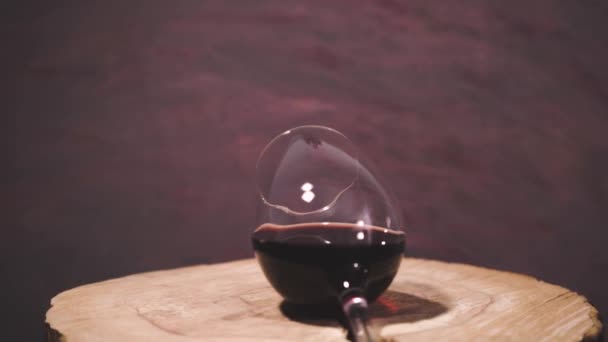 ラウンドでワインのガラスひびの入った木製のテーブル 360 美しい暗赤色背景 — ストック動画