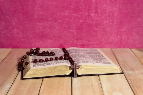 聖書と十字架新しい木製のテーブル 美しいピンクの壁の背景 宗教概念 — ストック写真