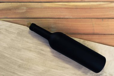 Siyah şişe kırmızı şarap yeni ve kırmızı ahşap bir masa üzerinde. Güzel arka plan