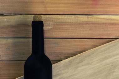 Siyah şişe kırmızı şarap yeni ve kırmızı ahşap bir masa üzerinde. Güzel arka plan