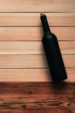 Siyah şişe kırmızı şarap yeni ve kırmızı ahşap bir masa üzerinde. Güzel arka plan