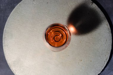 Bardak kırmızı şarap bir yuvarlak taş tabloda siyah bir şişe şarap. Güzel koyu kırmızı arka plan