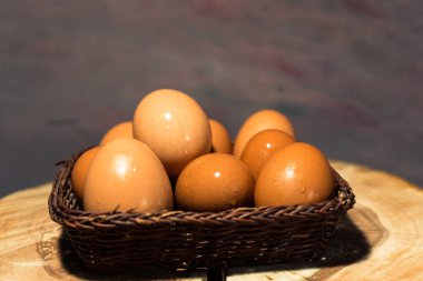 Yuvarlak ahşap bir masa üzerinde yumurta sepetle. Güzel koyu arka plan.