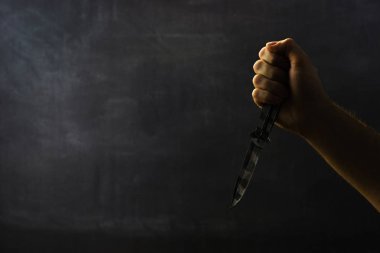Genç adam bir bıçak ile yaklaşık saldırı, koyu arka plan üzerinde.