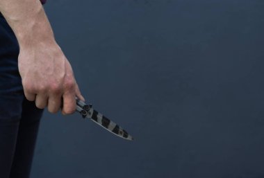 Genç adam bir bıçak ile yaklaşık saldırı, koyu arka plan üzerinde.