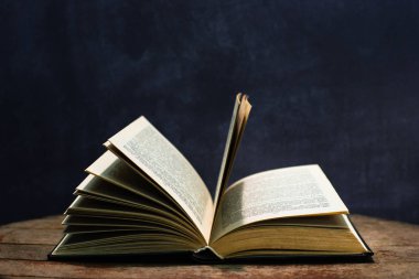 Yuvarlak ahşap bir masa üzerinde eski kitaplar. Güzel koyu arka plan.