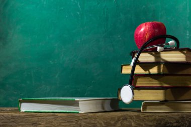 Eski kitaplar üzerinde meşe ahşap bir masa. Güzel koyu arka plan.