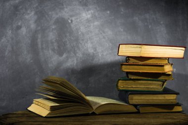 Eski kitaplar üzerinde meşe ahşap bir masa. Güzel koyu arka plan.